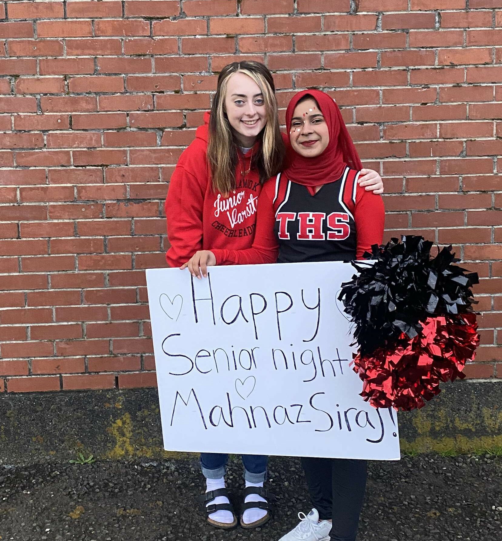 Mahnaz Posing With her cheer coach Outside Holding A Sign That Says  Happy Senior Night Manhaz Siraj