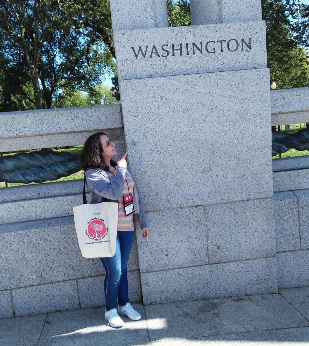 Manar standing in front of a stone sign that says 'Washington"