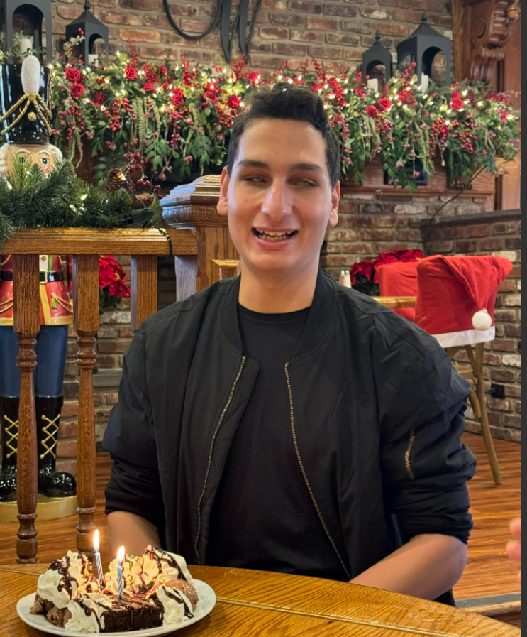 Mert smiling in a restaurant in front of desserts with birthday candles in them
