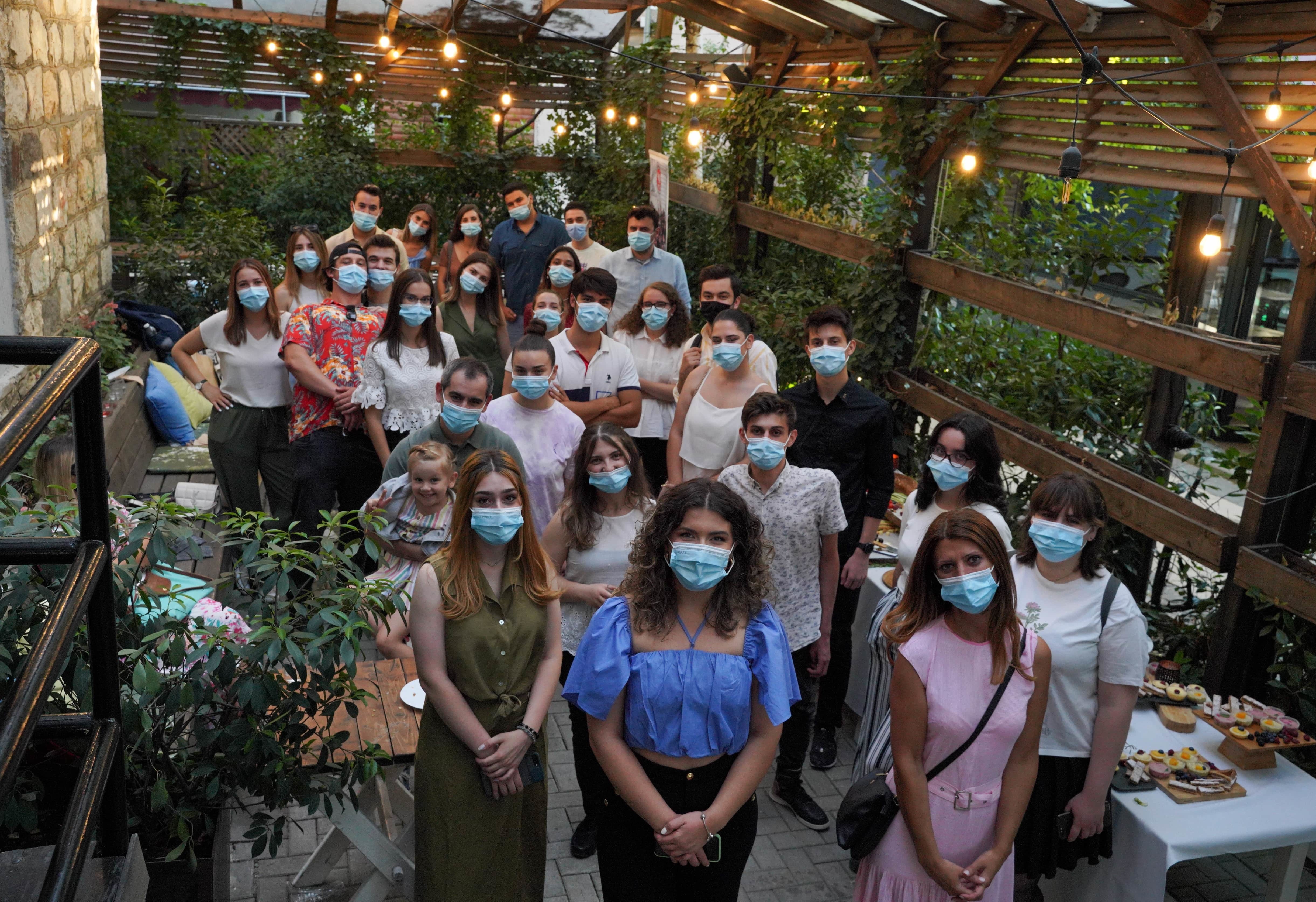 Alumni standing in a group with masks on in a restaurant. 