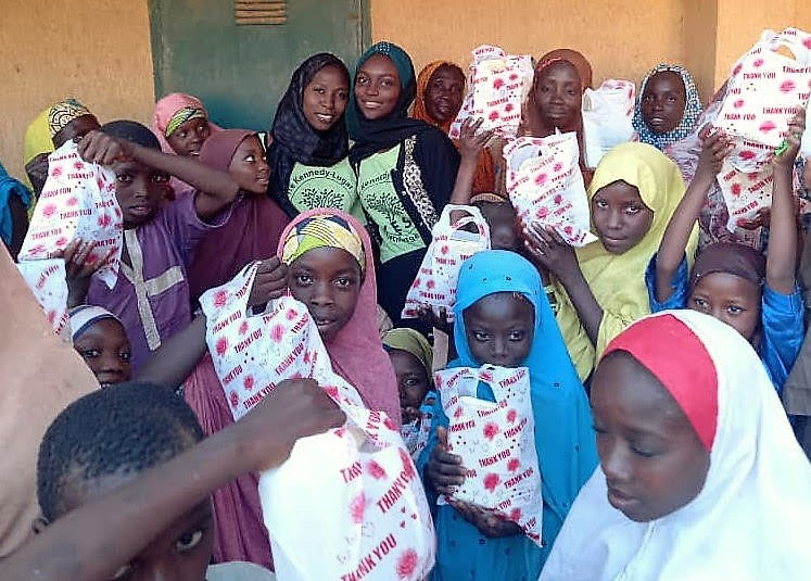 Women in Nigeria hold bags full of donations. 