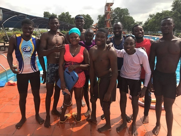 People stand in swim gear in front of a pool