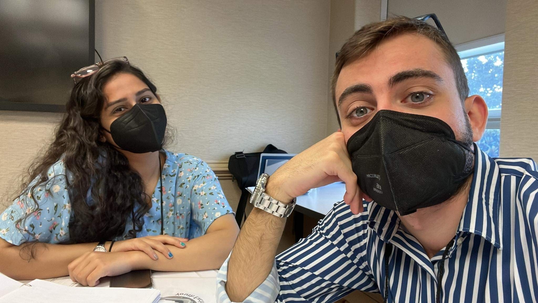 Qurat and Zaid wearing masks in a classroom and taking a selfie together. 