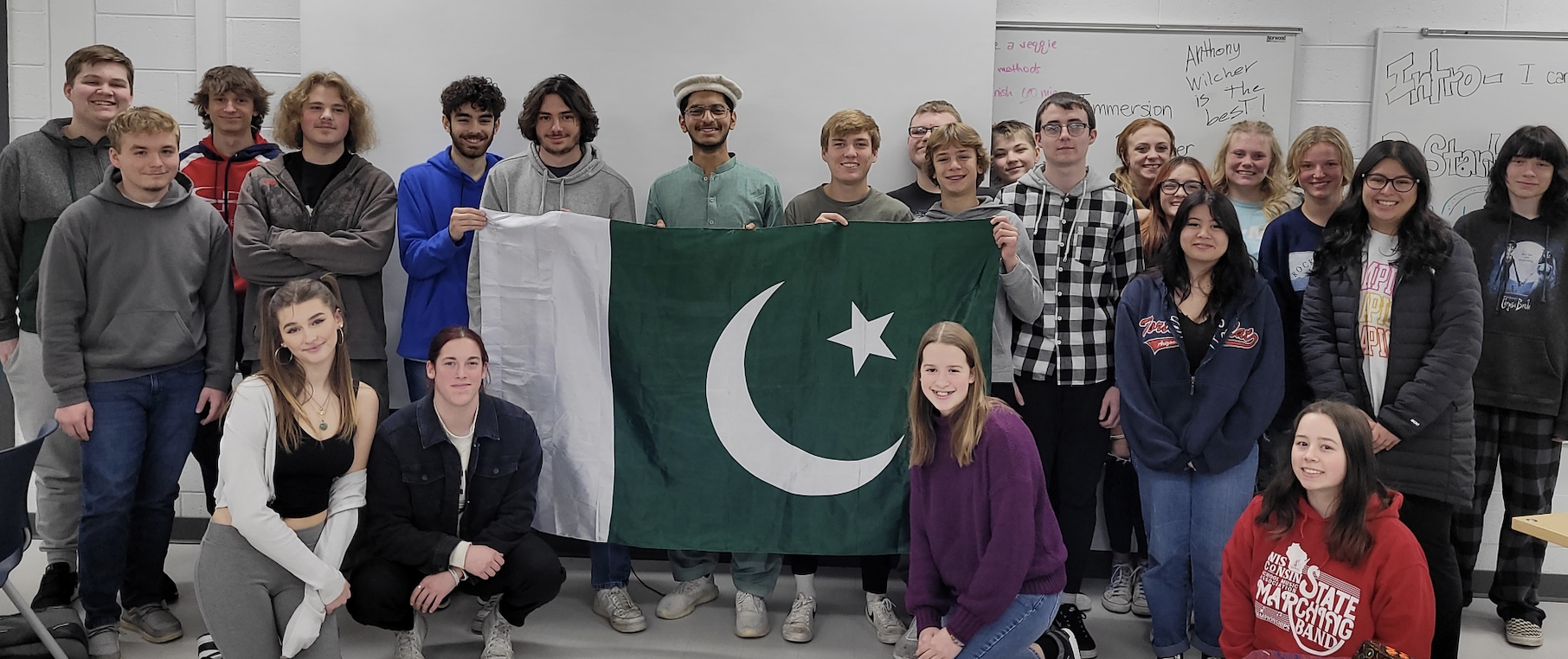Hashir, YES student, holding a Pakistani flag and standing next to his classmates.