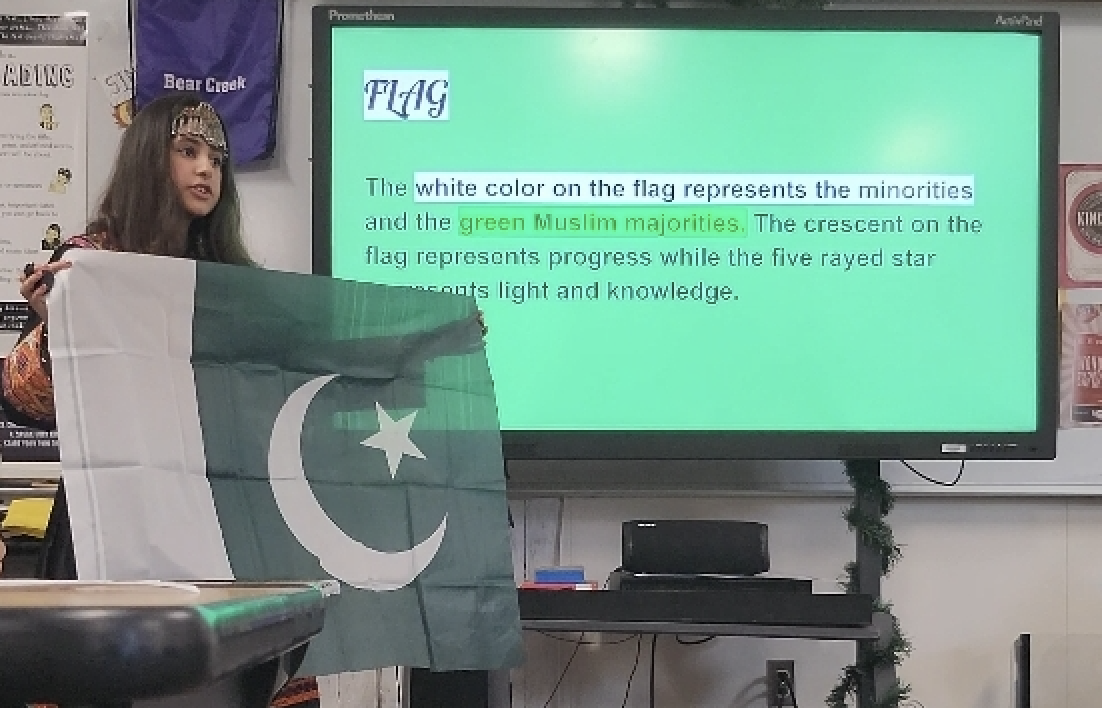 Wareesha holding a Pakistani flag and presenting at class during IEW.