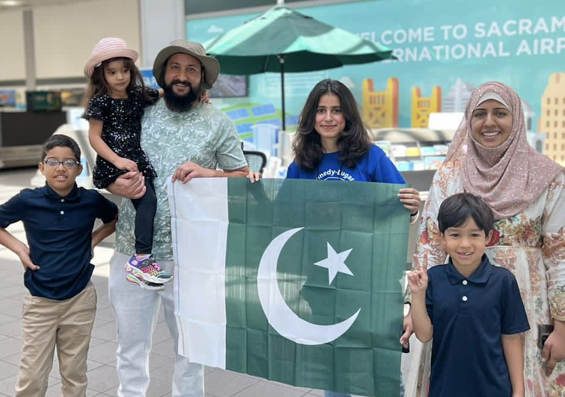 Wareesha holding the Pakistani flag and standing next to her host family at the airport.