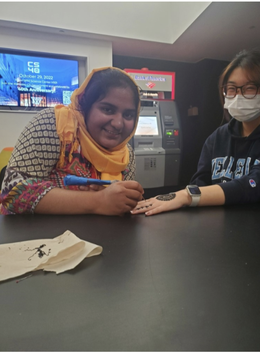 Maria applies a henna design to a classmate’s hand.