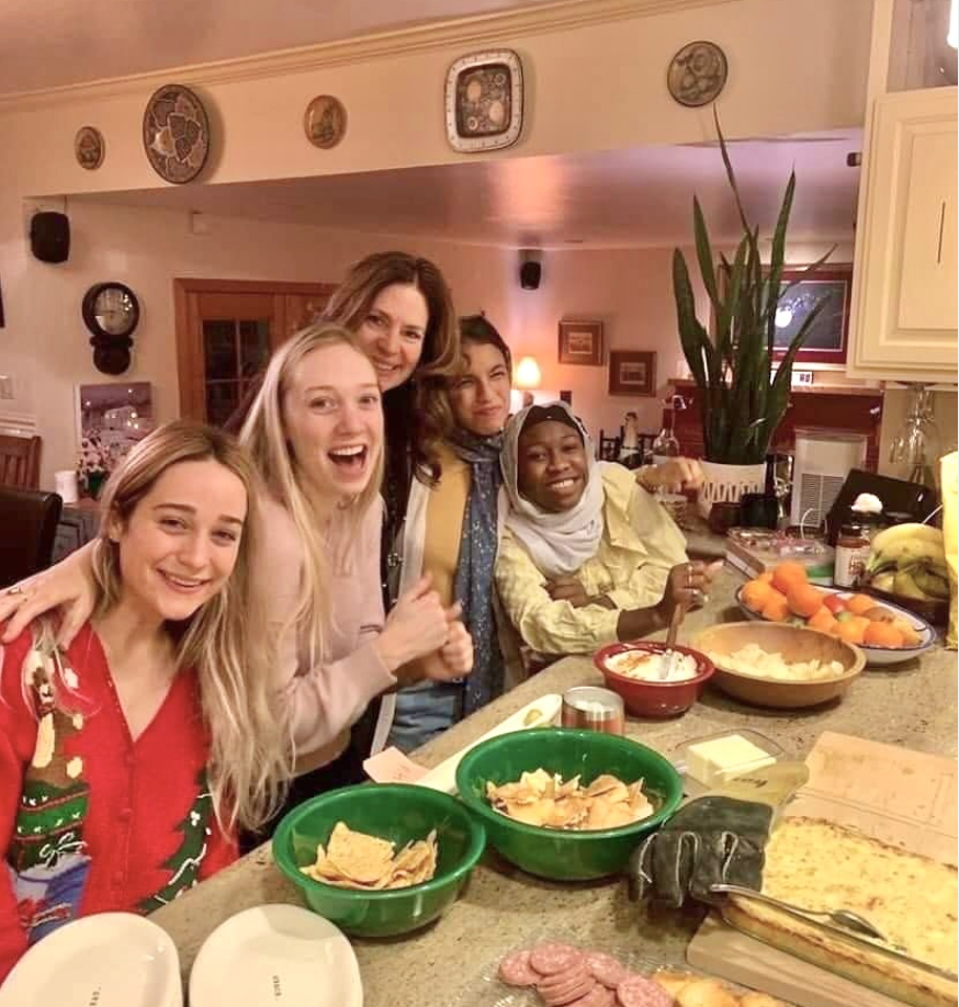 Nuhay with friends and host mom cooking at a kitchen counter