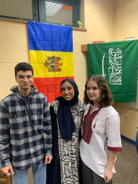 Seba From Saudi Arabia Poses With Two Classmates In Front Of Flags