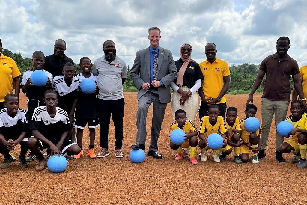 The US. Ambassador to Liberia stands with youth holding soccer balls