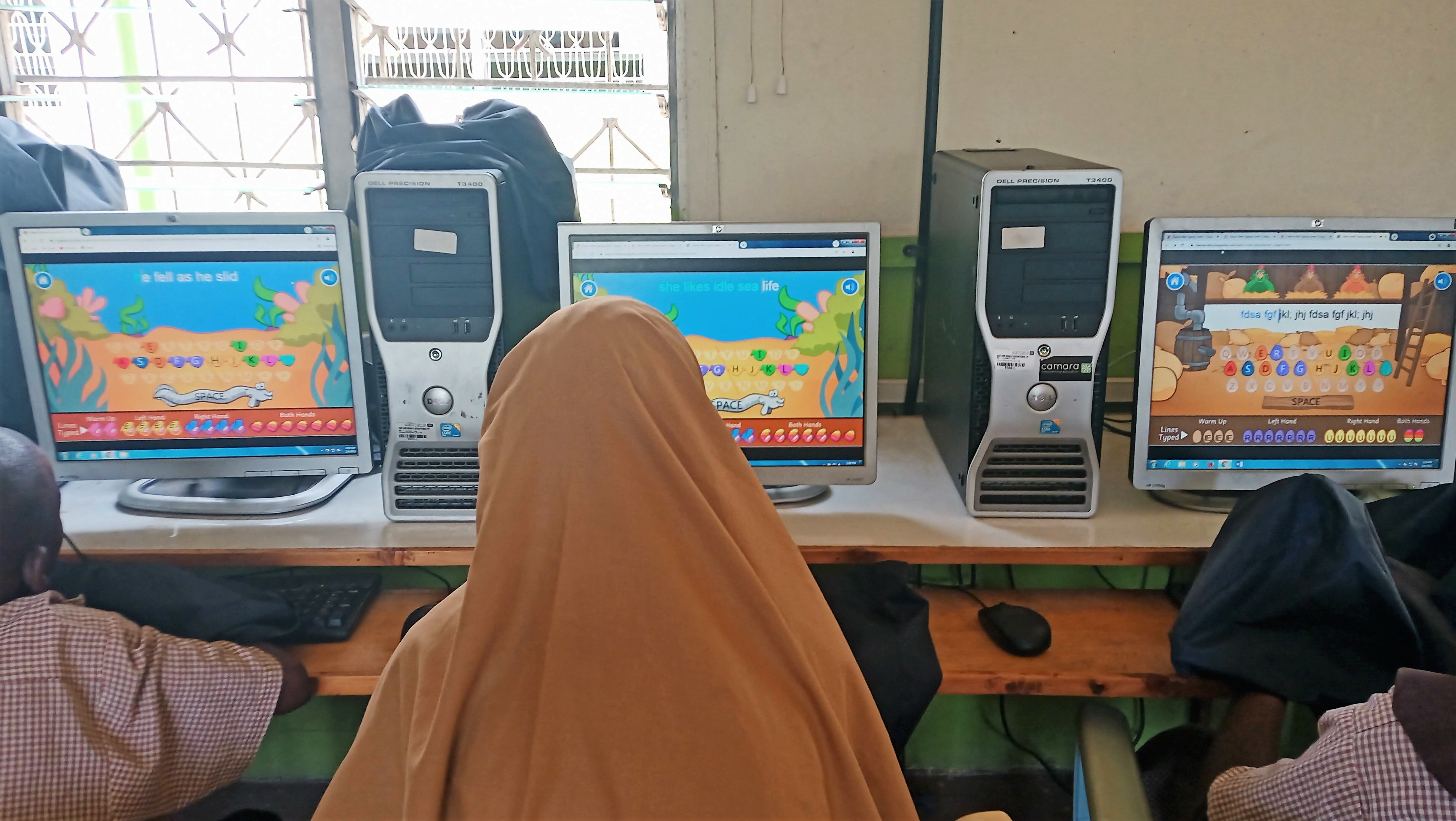 The Backs Of Three Children Doing English Activities On Computers