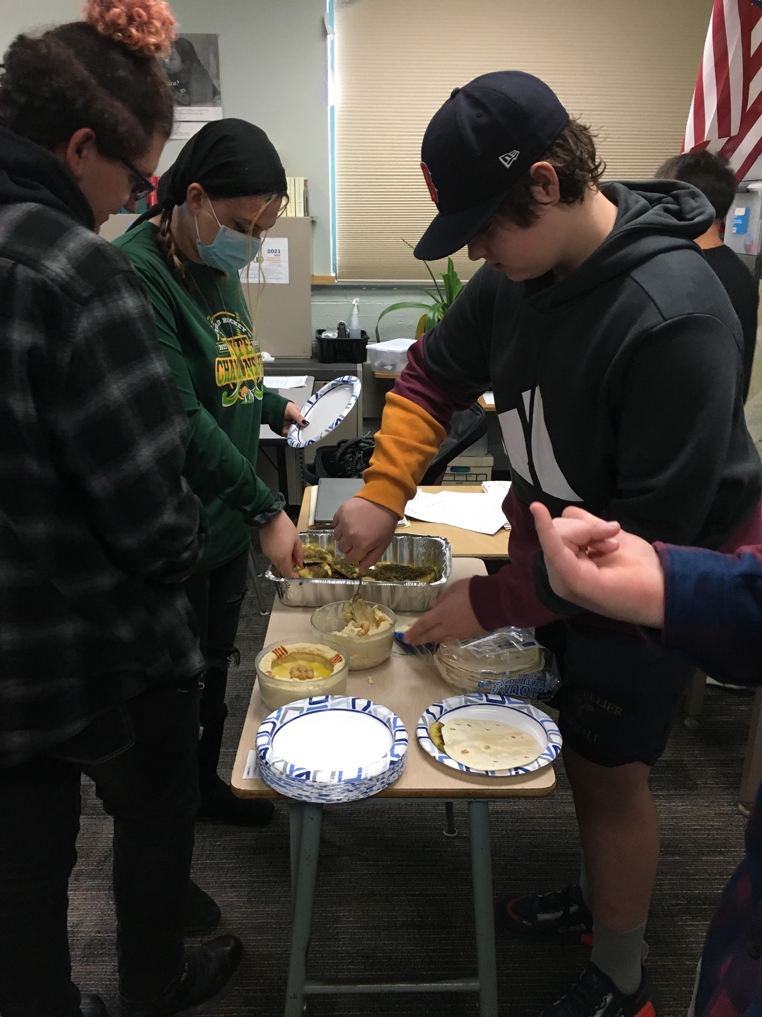 Three students filling plates with Lebanese food