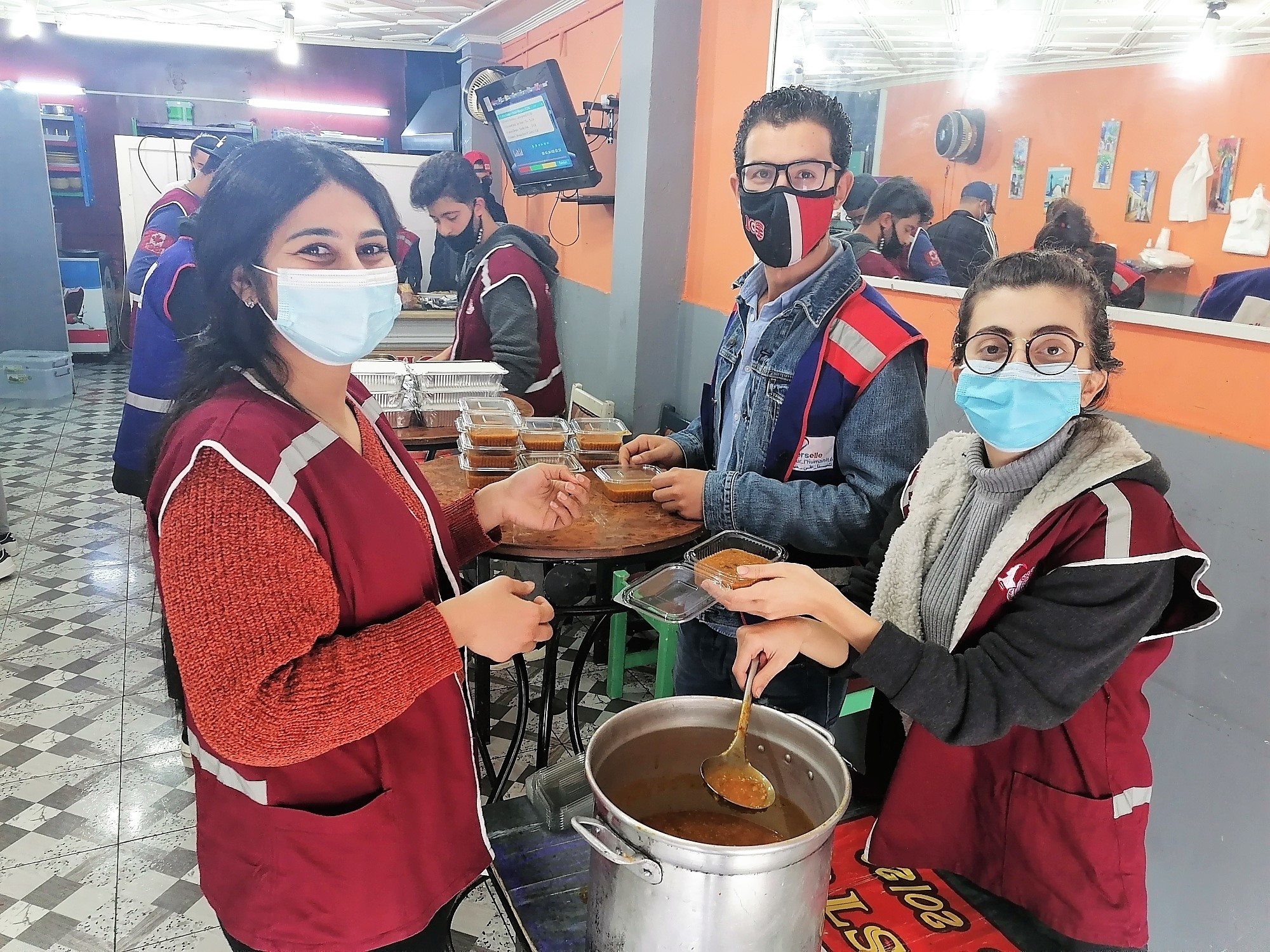 Alumni standing next to a table with masks on preparing to hand out soup. 