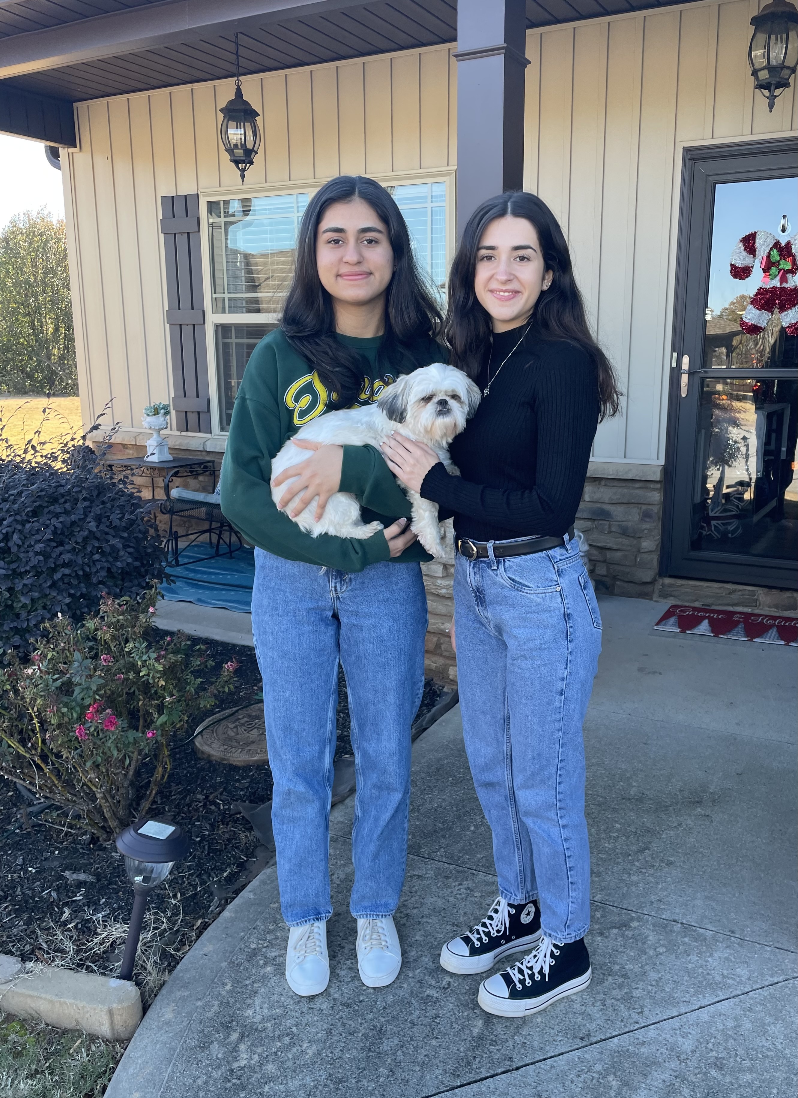 Two girls smiling holding a dog