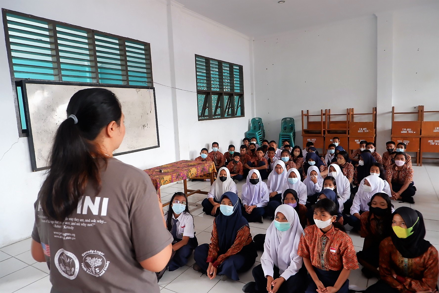 Viona conducting a presentation at the front of a classroom of many students in Indonesia