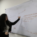 Dareen gesturing towards a whiteboard with debate terms written on it