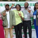 A group of five YES alumni volunteers including project lead poses together smiling and holding up the I love you hand sign in front of a banner