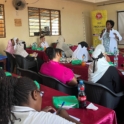 A doctor engaging the participants about cancer in a classroom theyre seated and theres a YES banner in the back
