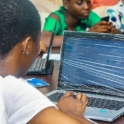 A Girl Is Looking At A Computer The Image Is From The Back So Looking At The Back Of Her Head