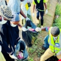 A group of volunteers and community members are holding garbage bags engaged in a community cleanup