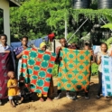 A Line Of People Hold Up Pieces Of Cloth That Have Been Tie Dyed With Batik Patterns