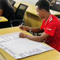 A participant sits at a table drafting a project timeline on a large sheet of paper