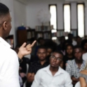 A speaker captured from the back speaking to the youth audience