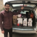 YES alumnus Ahmmed stands in front of the open trunk of a car 