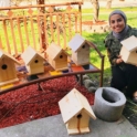 YES student Layan stands next to four bird houses she made and holds another one