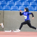 Alaa in a black hijab and blue shirt running on a track field