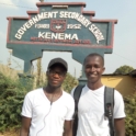 YES alumnus, Allieu standing with a friend in front of a sign that reads "Government Secondary School"