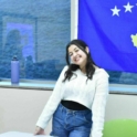 Almedina smiling in front of the Kosovo flag