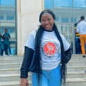 Alumna poses in front of building wearing YES tshirt