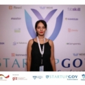 Amira in a black dress in front of a banner wall