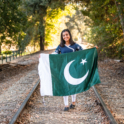 YES student Amna holds a Pakistani flag in the middle of an old railroad track