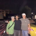 Anas stands with his host parents on either side of him. All three smile