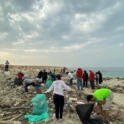 Jumana and other youth and YES alumni on a beach cleaning up trash from the rocks and shoreline. 