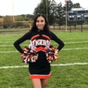Dalela standing on a football field in her cheer outfit.