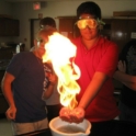 Abdulaziz and another student stand with goggles on with a large fire sparked in front of them