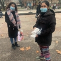 Two women, wearing masks, holding food donations
