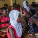 From A Side View Students Are Seated At Desks Looking Forward And Paying Attention