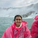 Fyka standing in front of Niagra Falls with a pink poncho on.