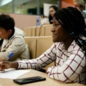 Ruth from Ghana sitting at a table with a panel of judges