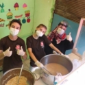 Three people stir large vats of food