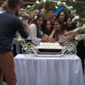 Group Of Alumni Surrounding Three Women Cutting A Cake On A Table 
