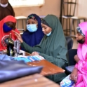 Group Of Participants Learning How To Sew A Bedsheet