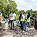 Group of volunteers carrying the collected garbage bins in pairs