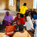 Group work with the students seating in circles Project Lead Nehemiah seating with them interacting and smiling