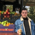 Filip stands outside an apple stand with an ice coffee in his hand