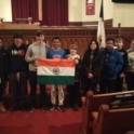 Atharva from India holds an Indian flag in a formal looking room